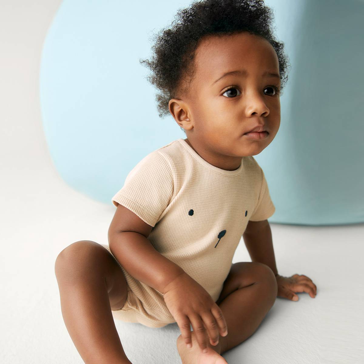 Chłopiec ubrany w beżowe body niemowlęce